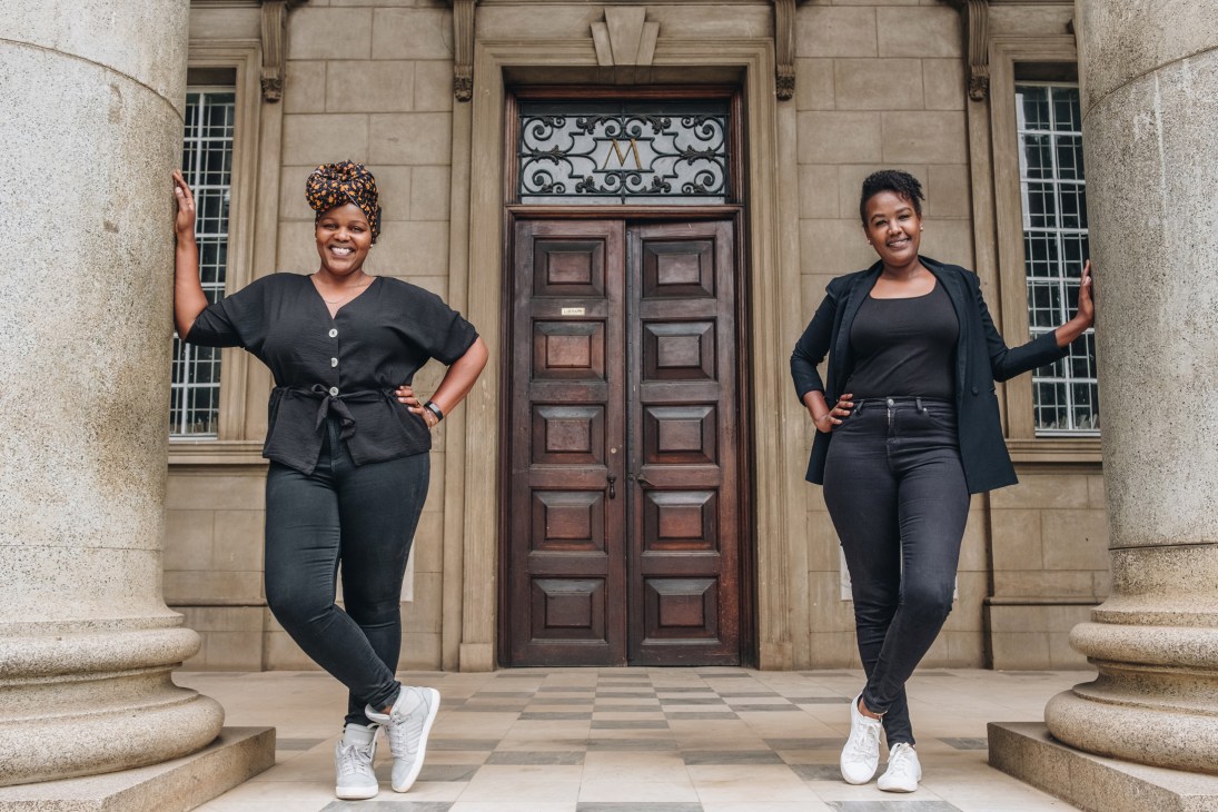 Angela Wachuka and Wanjiru Koinange standing in front of classical columns at McMillan Memorial Library in Nairobi