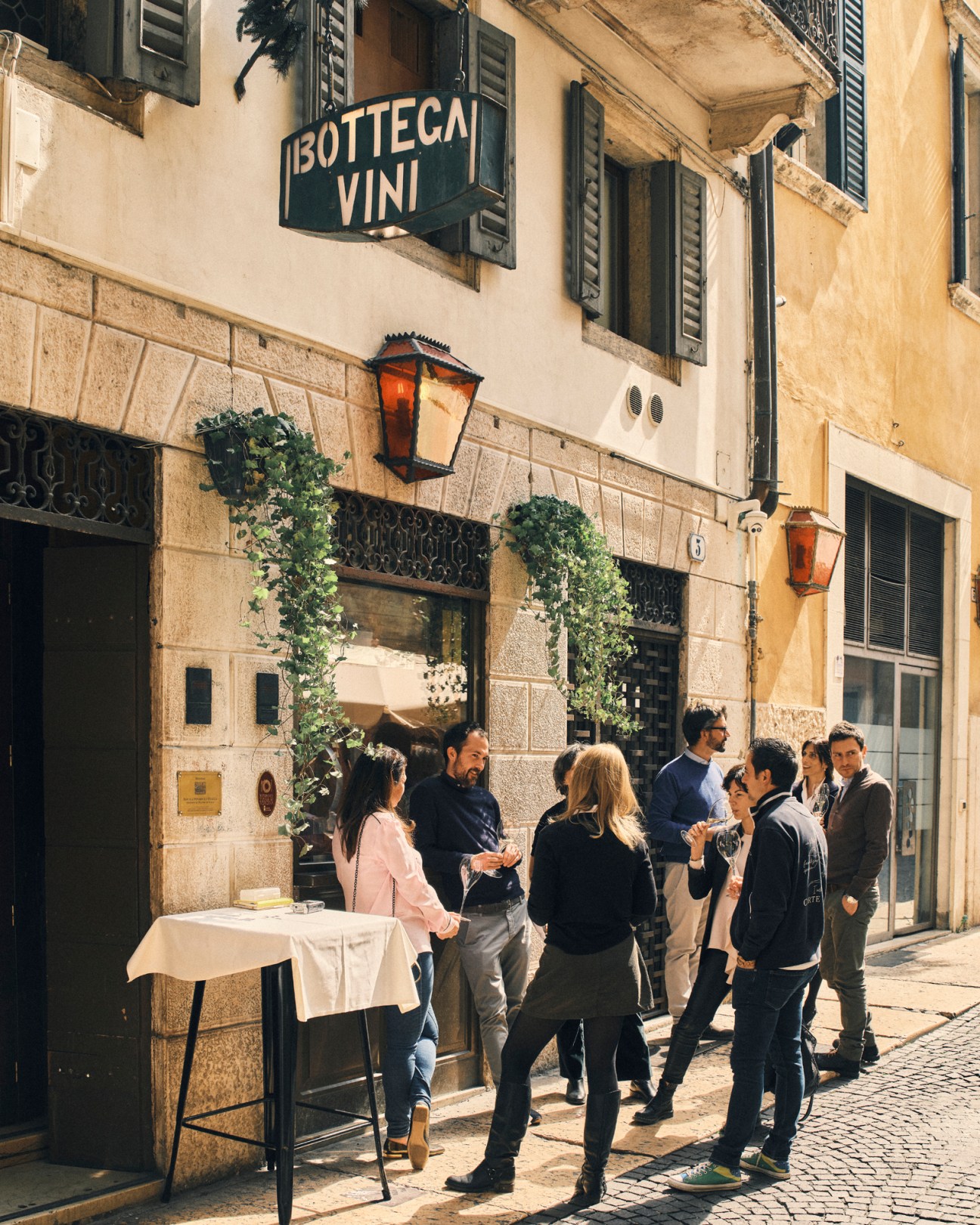 People gathering outside Antica Bottega del Vino wine bar in Verona with outdoor table setup