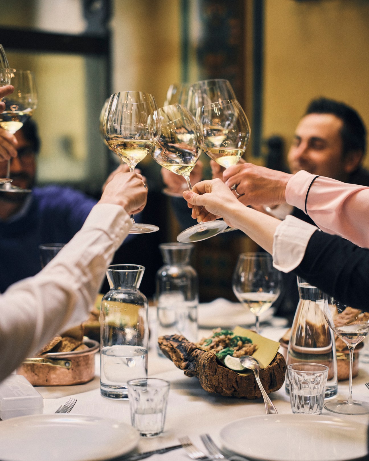 Wine producers raising glasses in a toast over appetizers at lunch