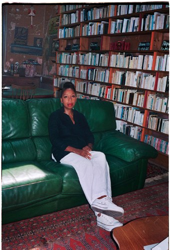 Woman sitting on green leather sofa in front of bookshelf