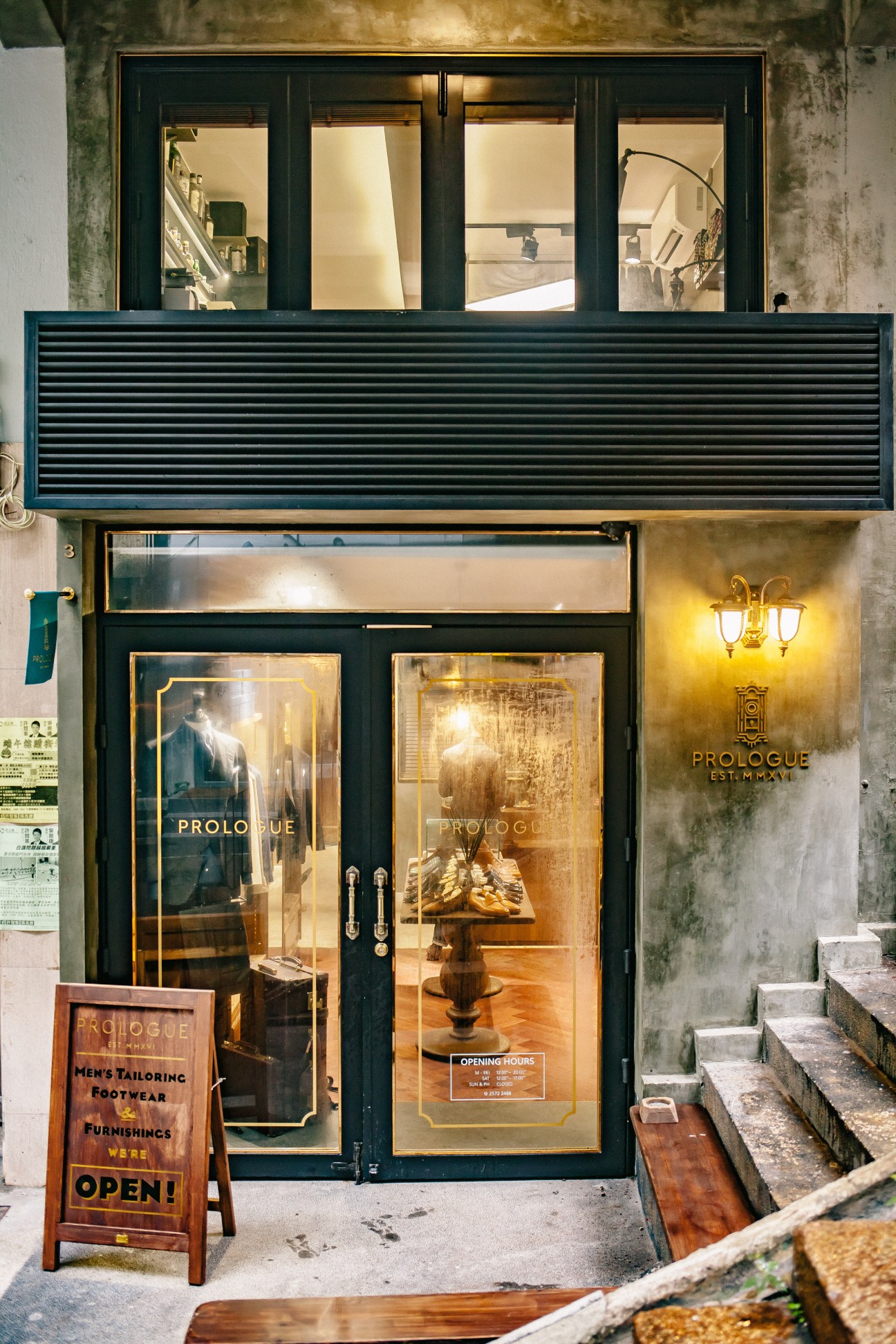 Prologue storefront in Hong Kong with dark green facade, gold signage and display windows showcasing menswear and tailoring.