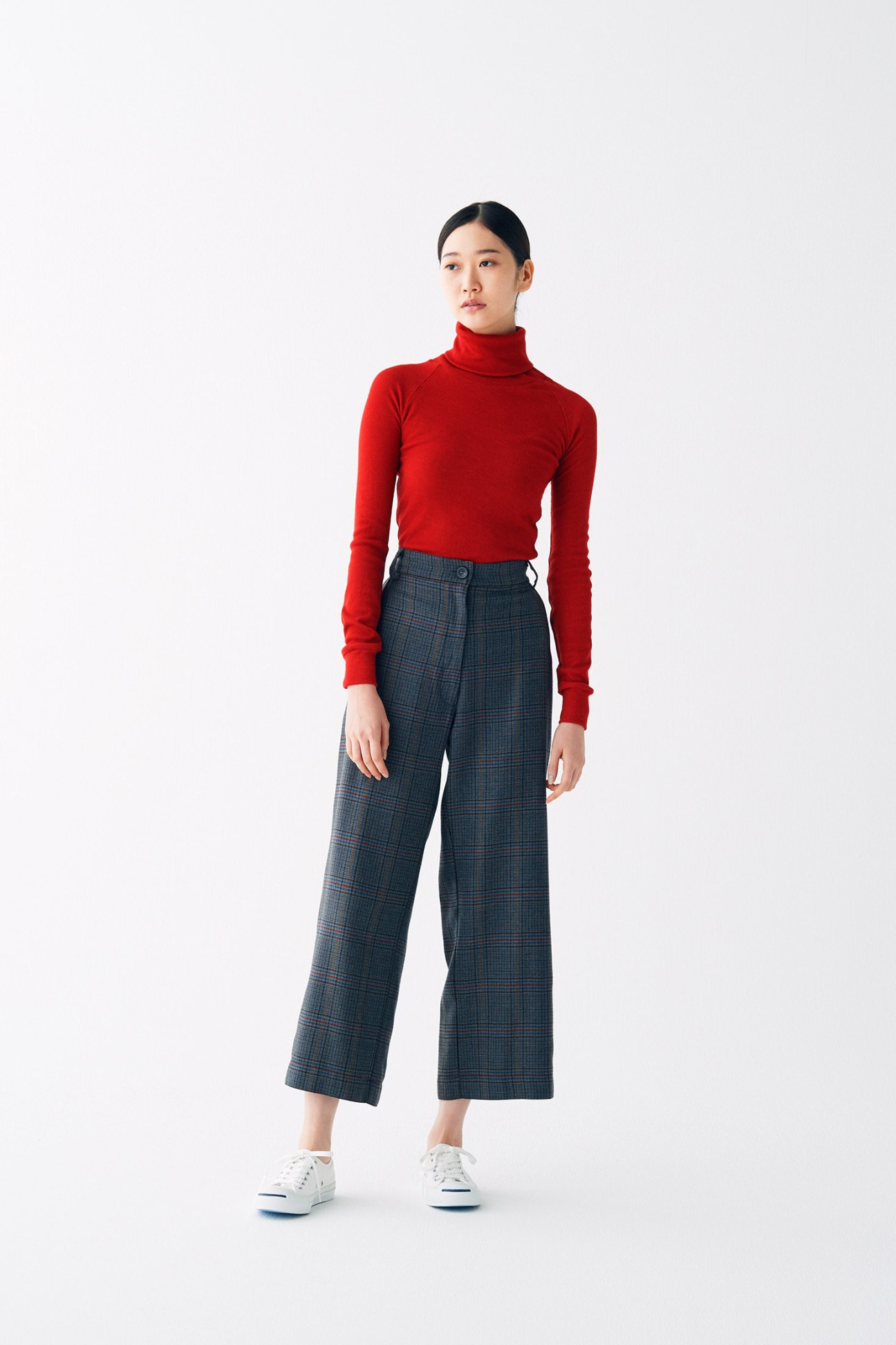 Woman wearing red turtleneck and plaid cropped trousers with white sneakers