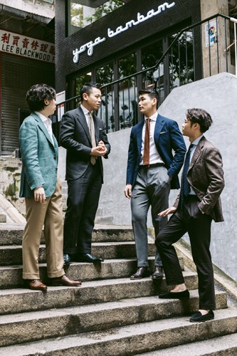 Chris Tang and colleagues at Prologue menswear shop in Hong Kong discussing made-to-order suits on exterior steps.