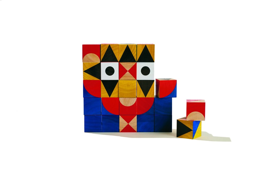 Colorful wooden building blocks by Miller Goodman arranged in creative face-like shapes.