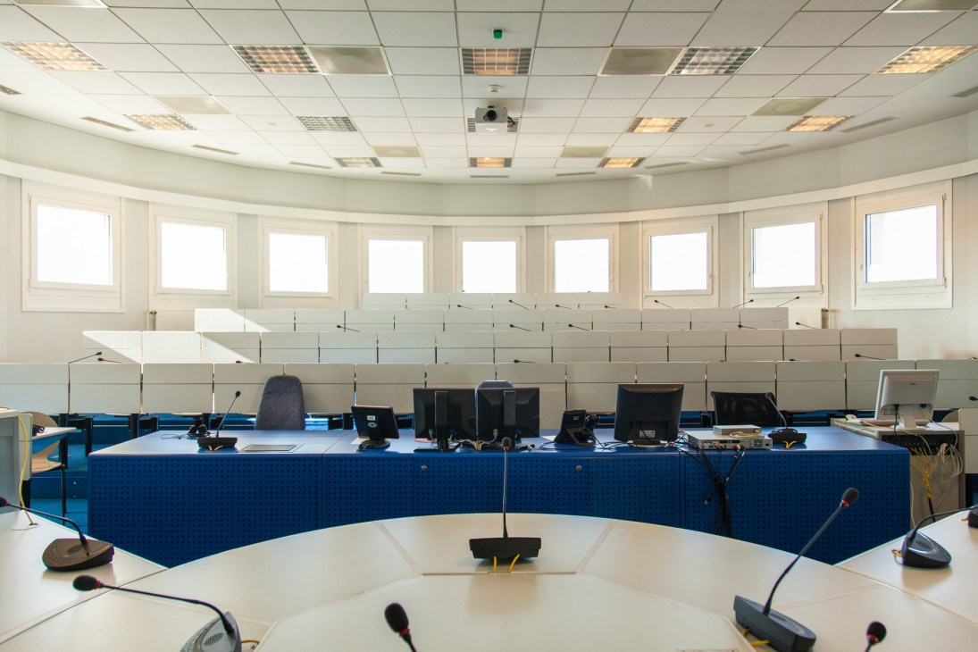 Interpretation room with elevated booth containing microphones, computers, and equipment for simultaneous translation training.