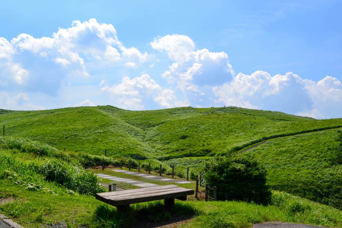Wooden bench overlooking rolling green hills and volcanic crater landscape at Daikanbo