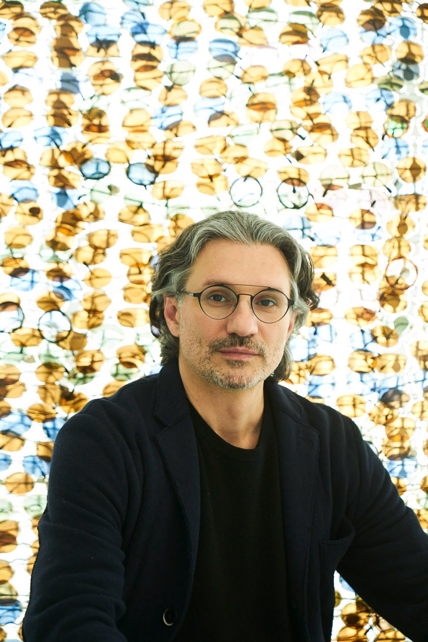Vladimiro Baldin, Safilo's chief product design and creation officer, poses against a background of colorful eyeglass frames.