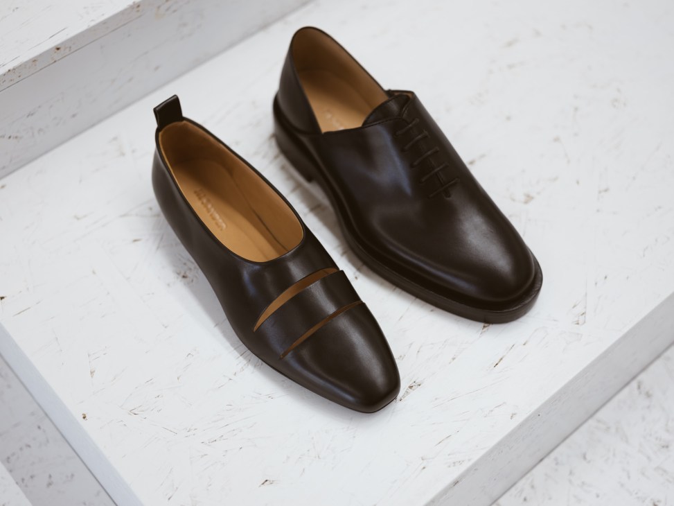 Two brown leather slip-on shoes displayed on a white wooden surface.