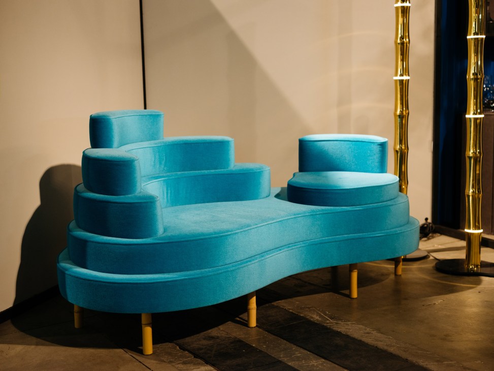 Turquoise upholstered modular seating installation with brass lighting by Nicolas Schuybroek for Hullebusch.