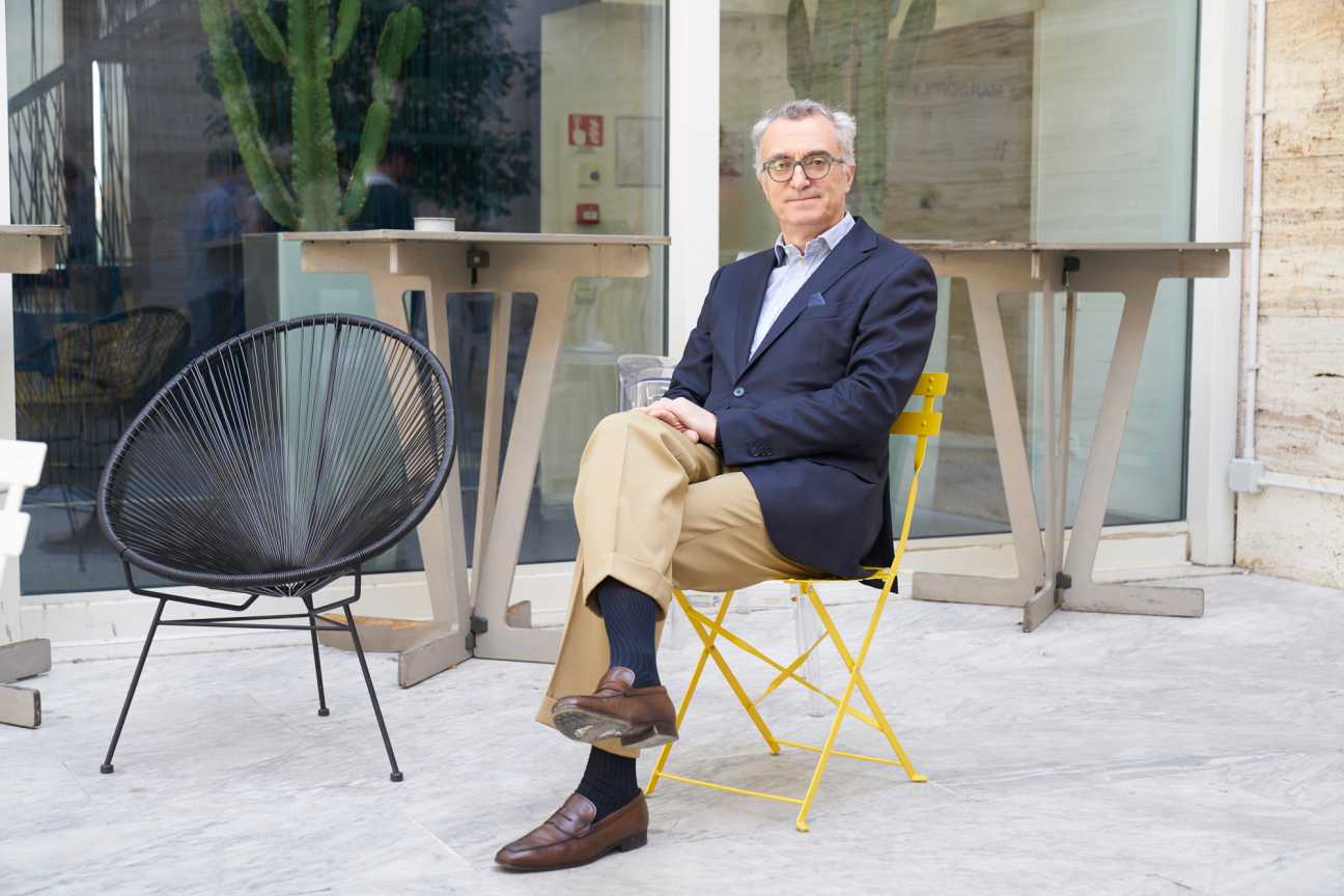 Luigi Capello, founder of Luiss Enlabs, sits on a yellow chair outside a modern glass-fronted building.