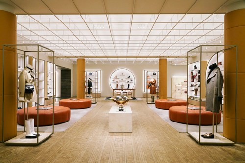 Interior of Tod's Studios Milan flagship store with minimalist design, orange seating, wooden flooring and display cases.