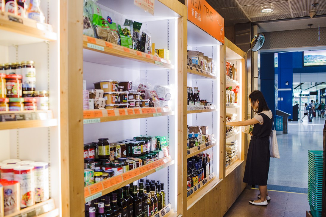 Woman shopping at Farm Fresh 330 grocery store shelves stocked with organic products in Hong Kong.