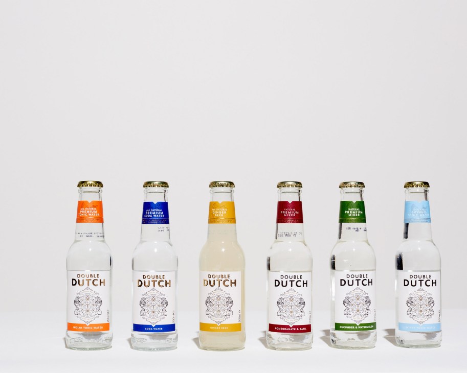 Six glass bottles of Double Dutch Drinks mixers in various flavors with gold caps and colored labels.