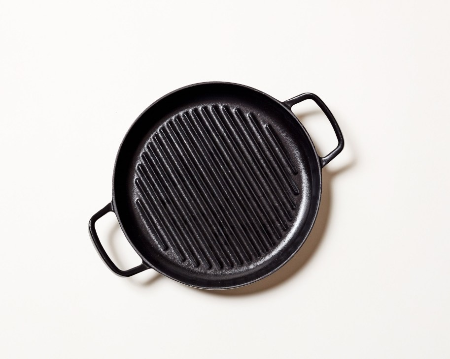 Black cast iron griddle pan with ridged cooking surface and two side handles.