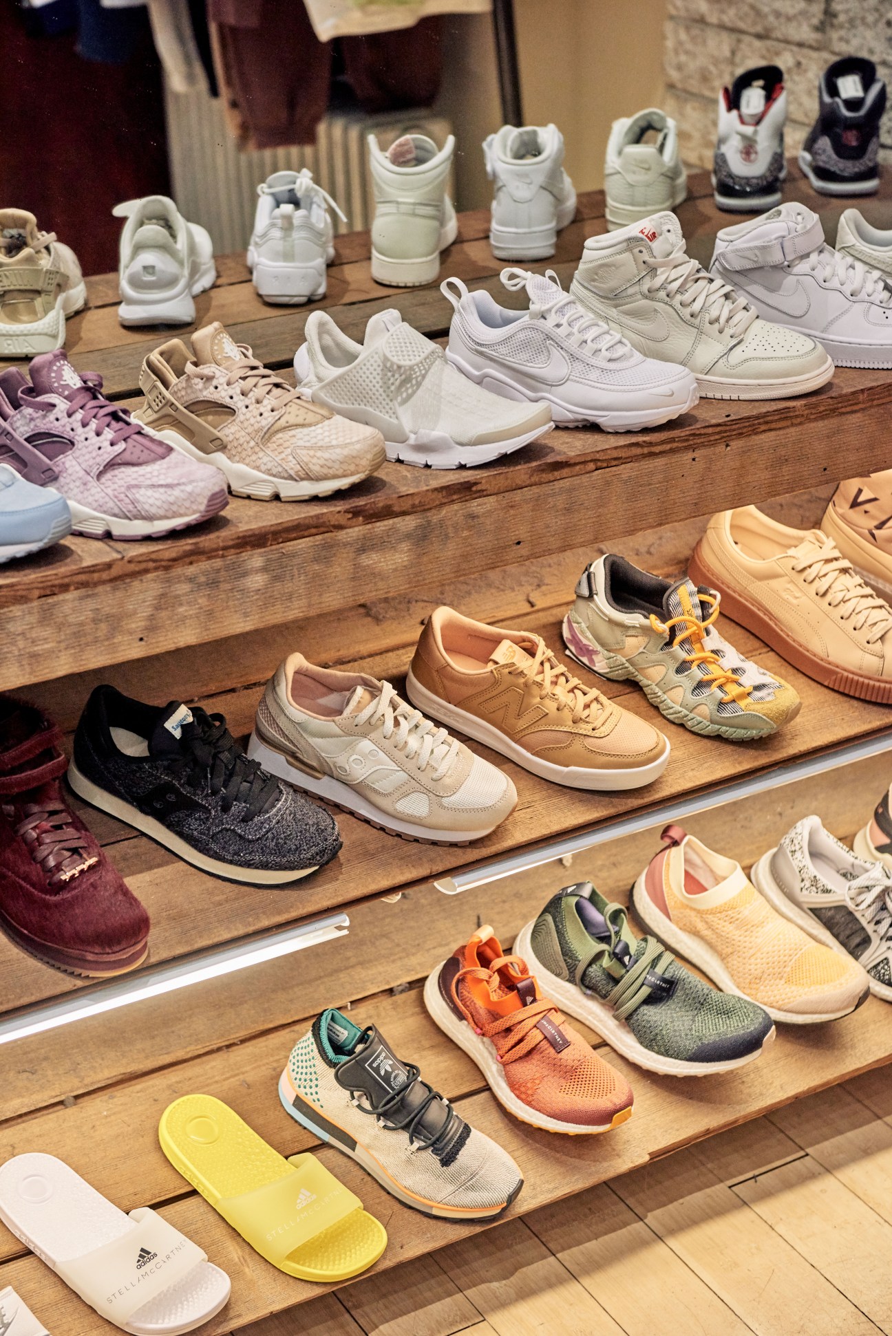 Curated collection of sneakers and athletic shoes displayed on wooden shelves in a retail setting.