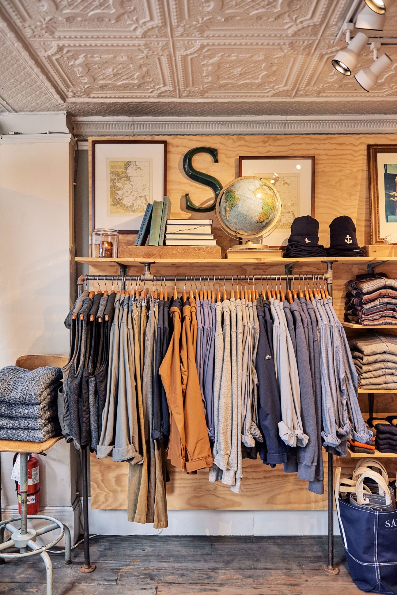 Retail interior of Sault menswear shop displaying clothing on wooden hangers with shelving and decorative items above.