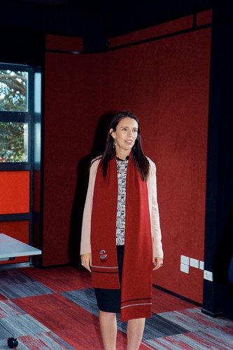 Woman in red coat standing against red wall in modern interior space