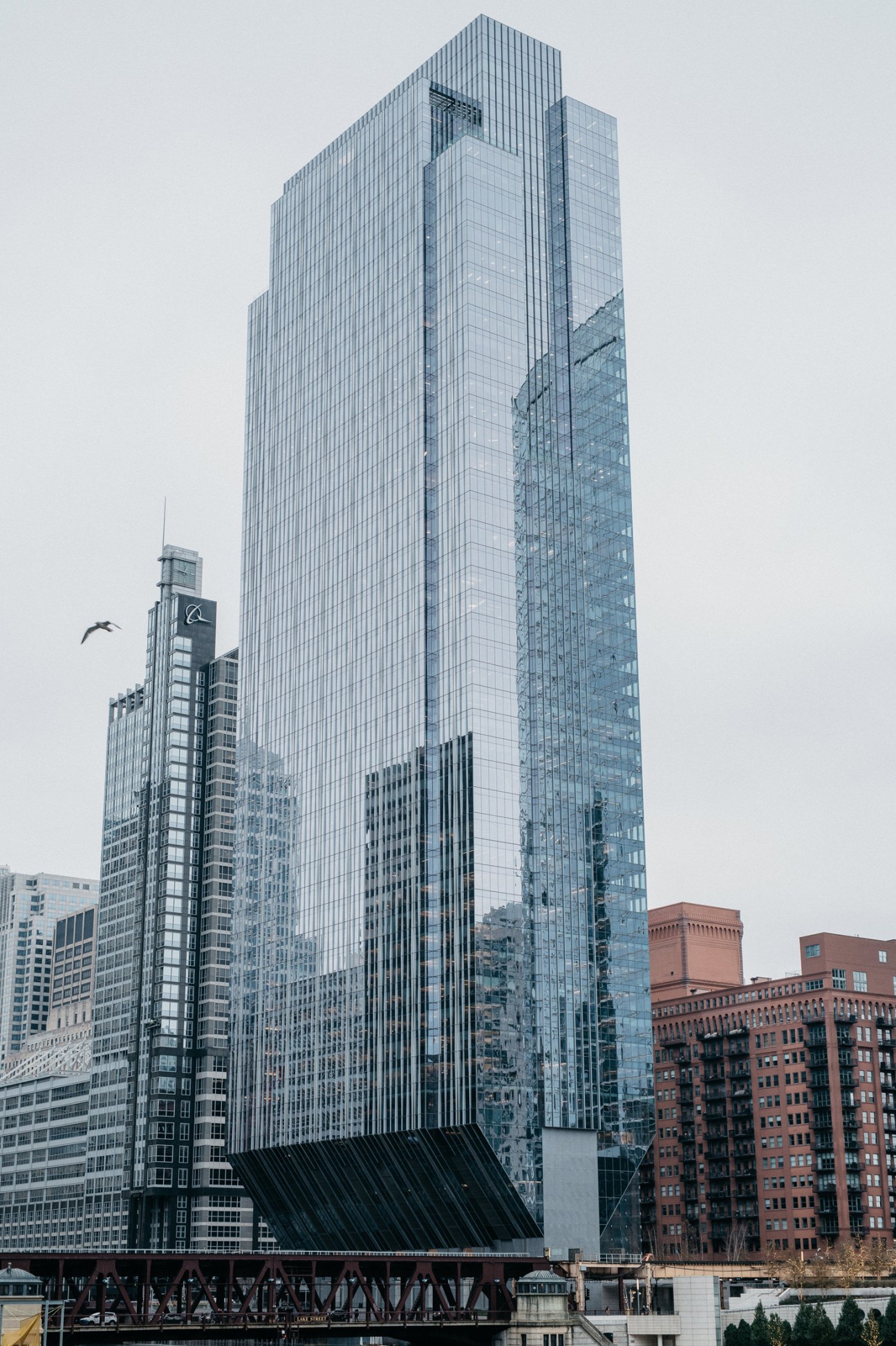 Modern glass skyscraper with vertical ribbing rises above historic brick buildings in Chicago's skyline.