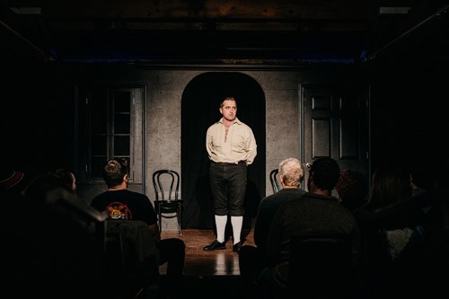 A performer stands on stage in front of an audience in The iO Theater, Chicago's improv comedy venue.