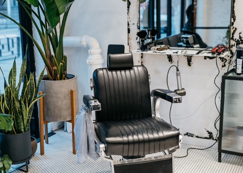 Interior of Blind Barber barbershop with black leather barber chair and potted plant.