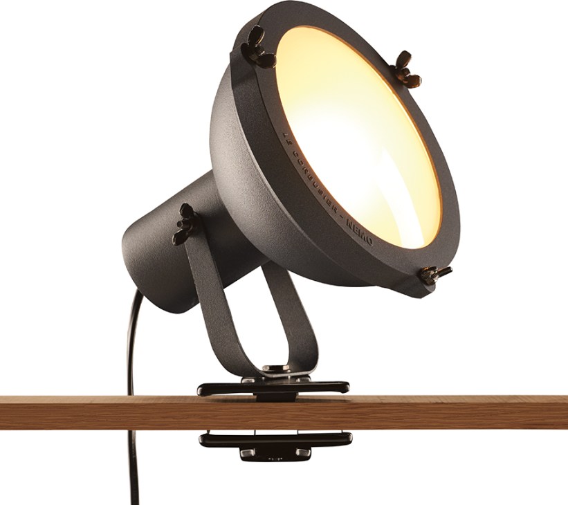 Nemo clip lamp with adjustable dark metal head and glowing warm light mounted on wooden shelf edge.