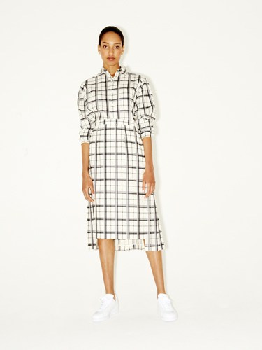 Woman wearing a white grid-pattern button-down shirt dress with white sneakers.