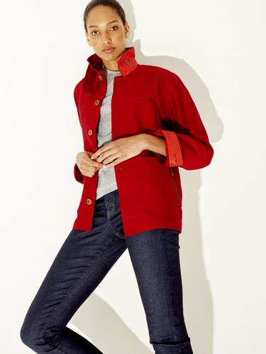 Woman wearing a bright red button-up jacket over a grey top and dark jeans.
