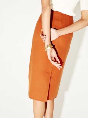 Woman wearing orange skirt holding architectural bracelets by Ferian jewelry brand