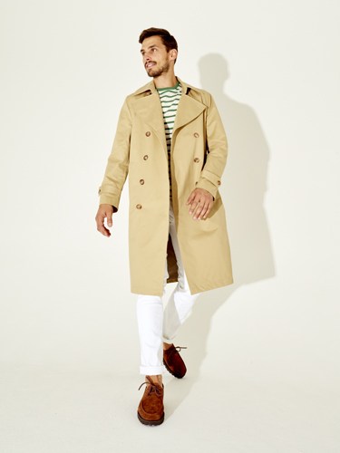 Man wearing a beige double-breasted trench coat, striped shirt, and brown shoes, representing Sunflower menswear.