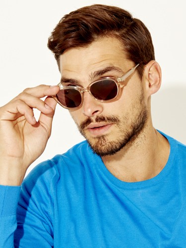 Man wearing clear-framed sunglasses with amber-tinted lenses and a blue t-shirt