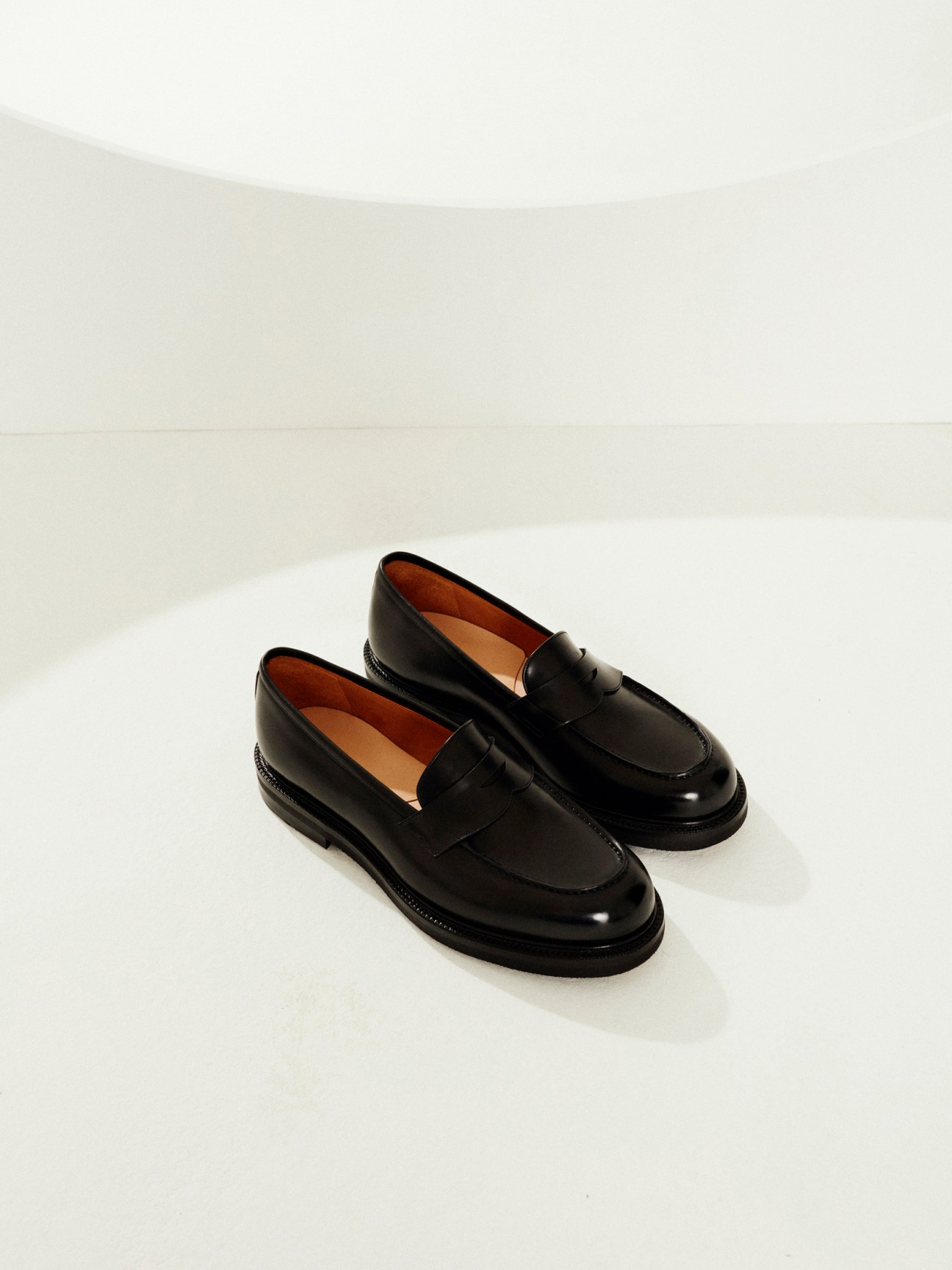 Pair of black leather loafers with chunky soles displayed on white surface.