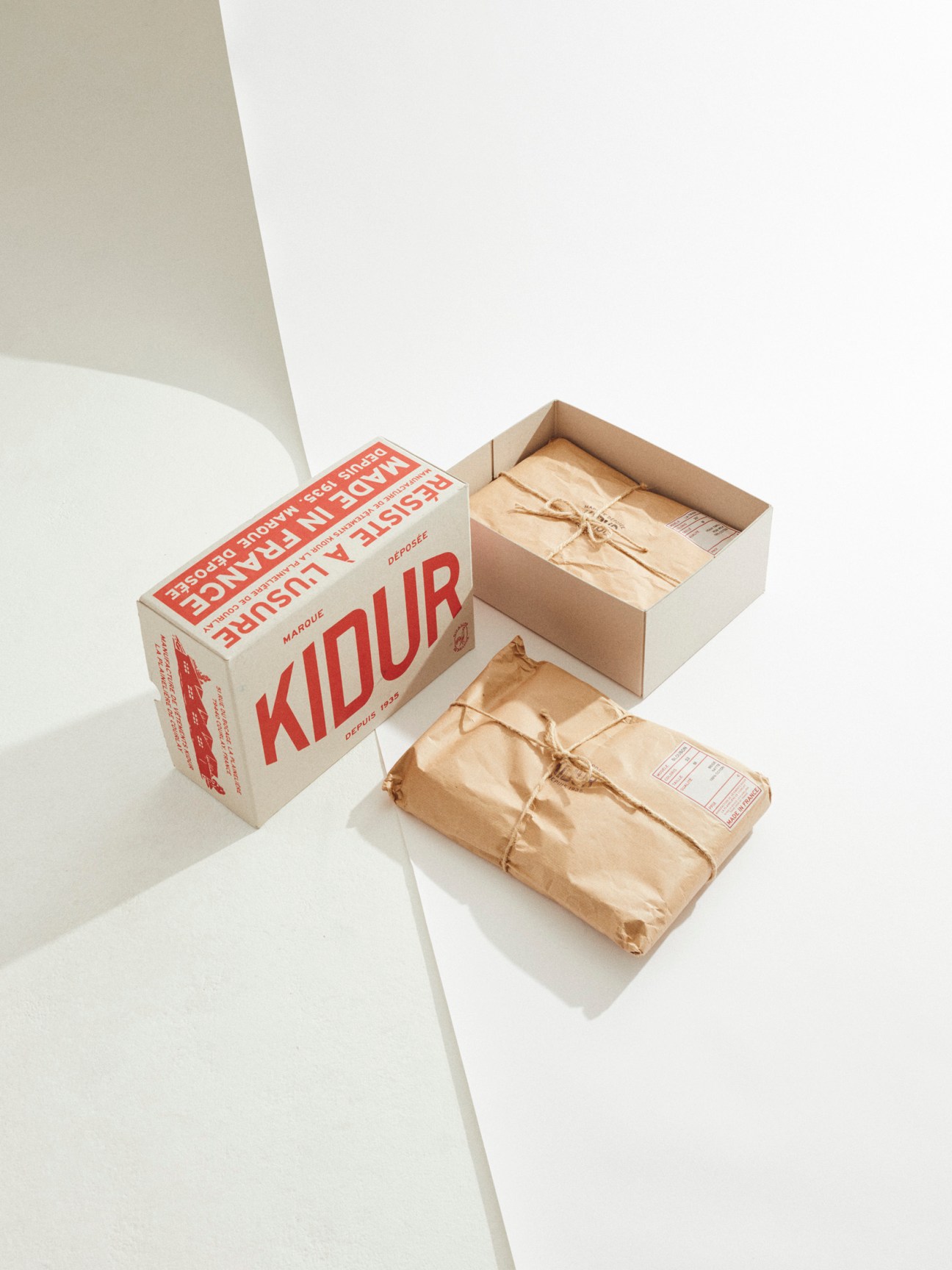 Kidur packaging with recycled paper box and kraft paper wrapped garments tied with twine