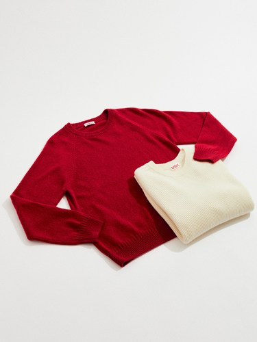 Two knit sweaters displayed on a light background: a burgundy long-sleeved crew neck and a cream-colored sleeveless vest by Tricot.