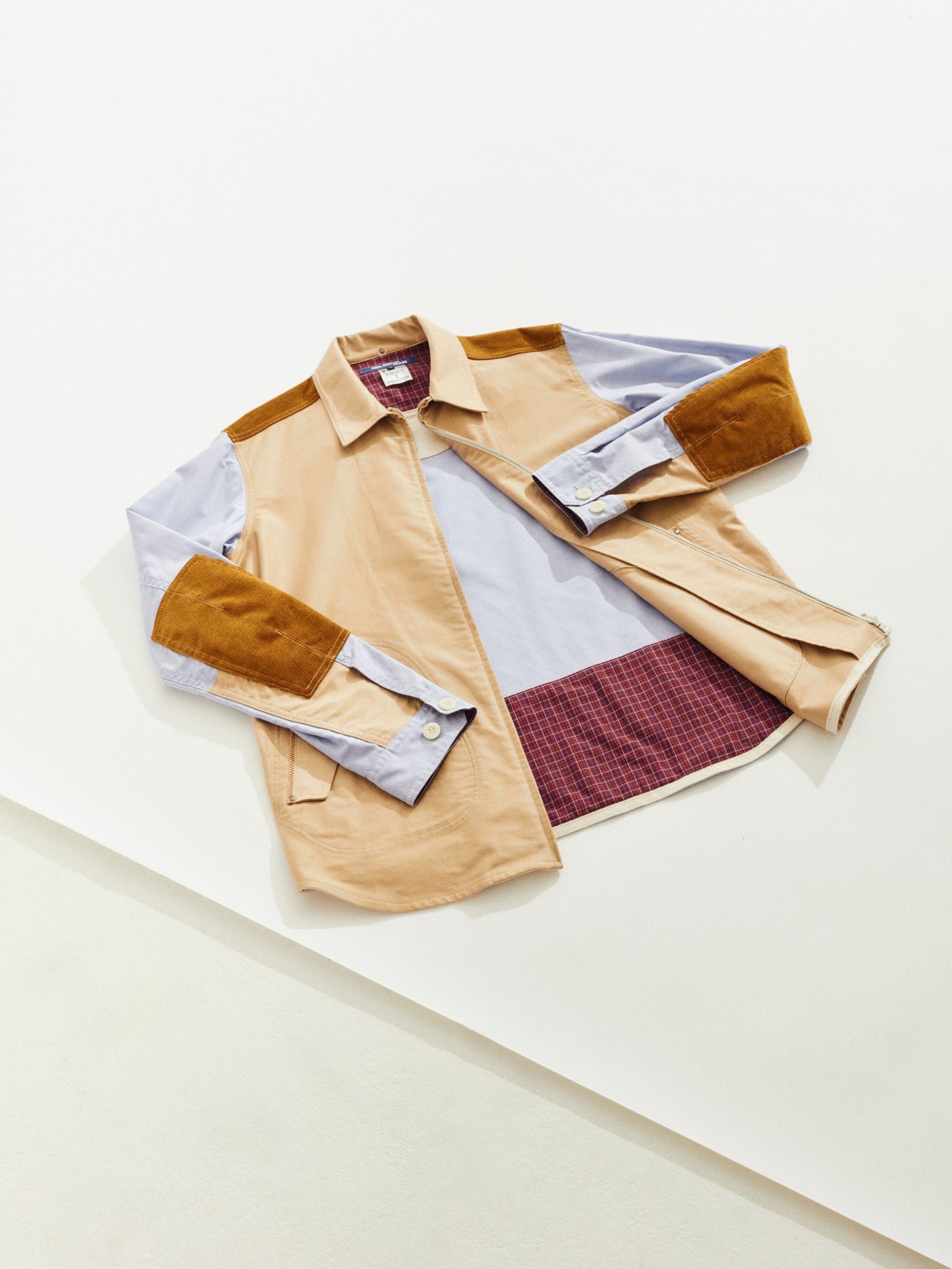 Junya Watanabe deconstructed shirt layered flat with suede cuffs and plaid interior visible.