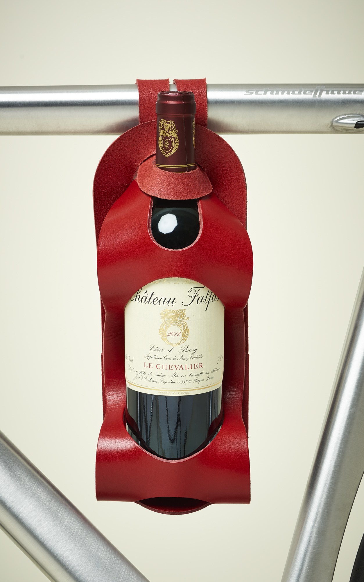Red leather wine bottle carrier holding a bottle of Château Falfas with a dark red wax seal and foil capsule.