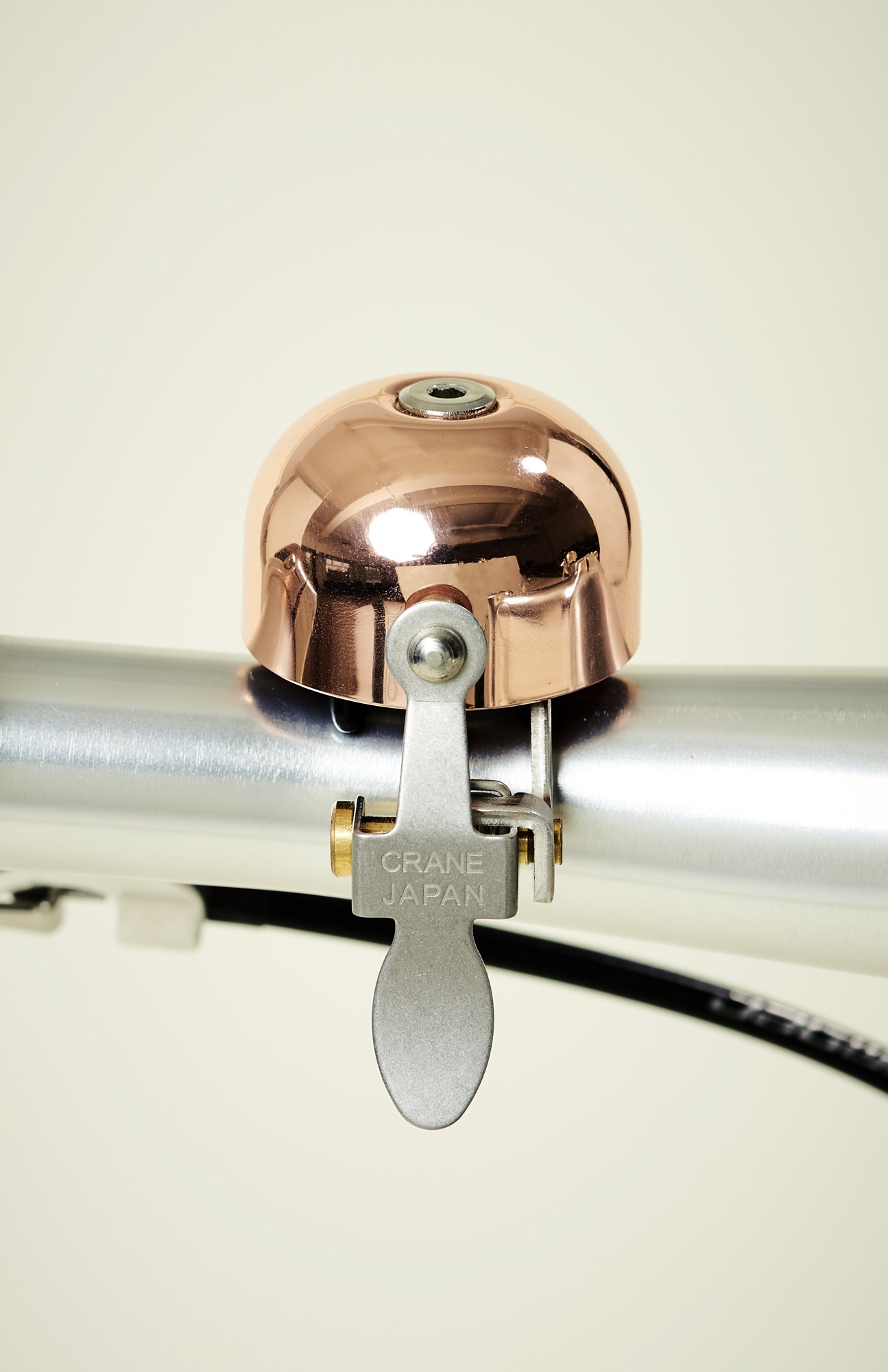 Crane Bell Co copper-colored bicycle bell mounted on handlebars with silver lever mechanism.