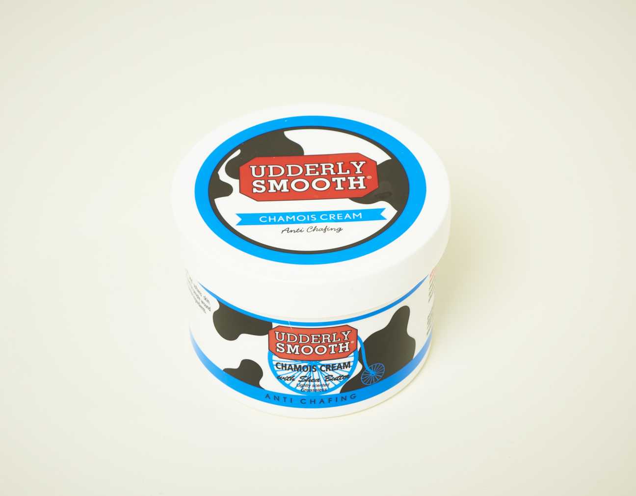 Udderly Smooth Chamois Cream anti-chafing moisturiser in white container with blue label and cow design.