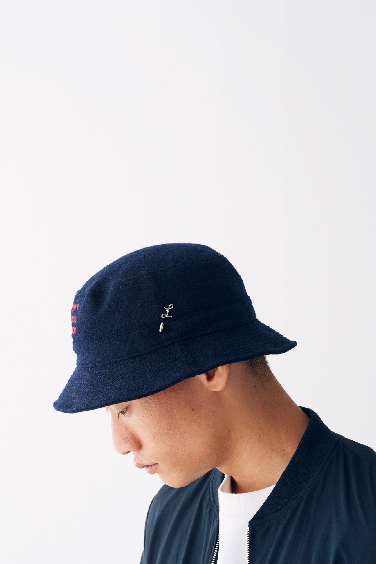 Person wearing a navy bucket hat with embroidered branding and red text on the side.