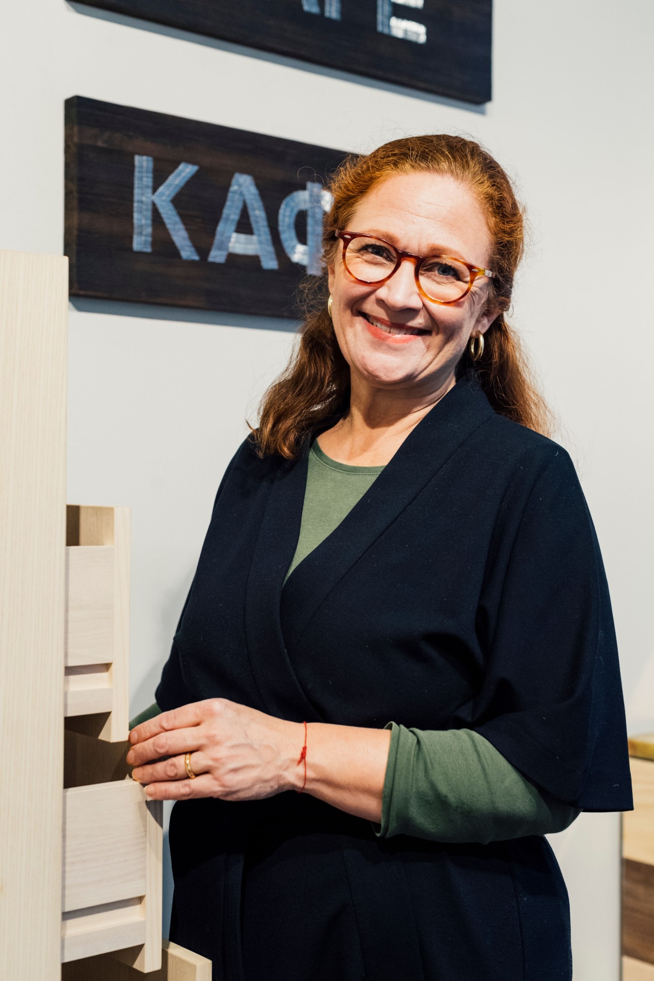 Woman with reddish-brown hair and glasses smiling at Lokal shop in Helsinki.