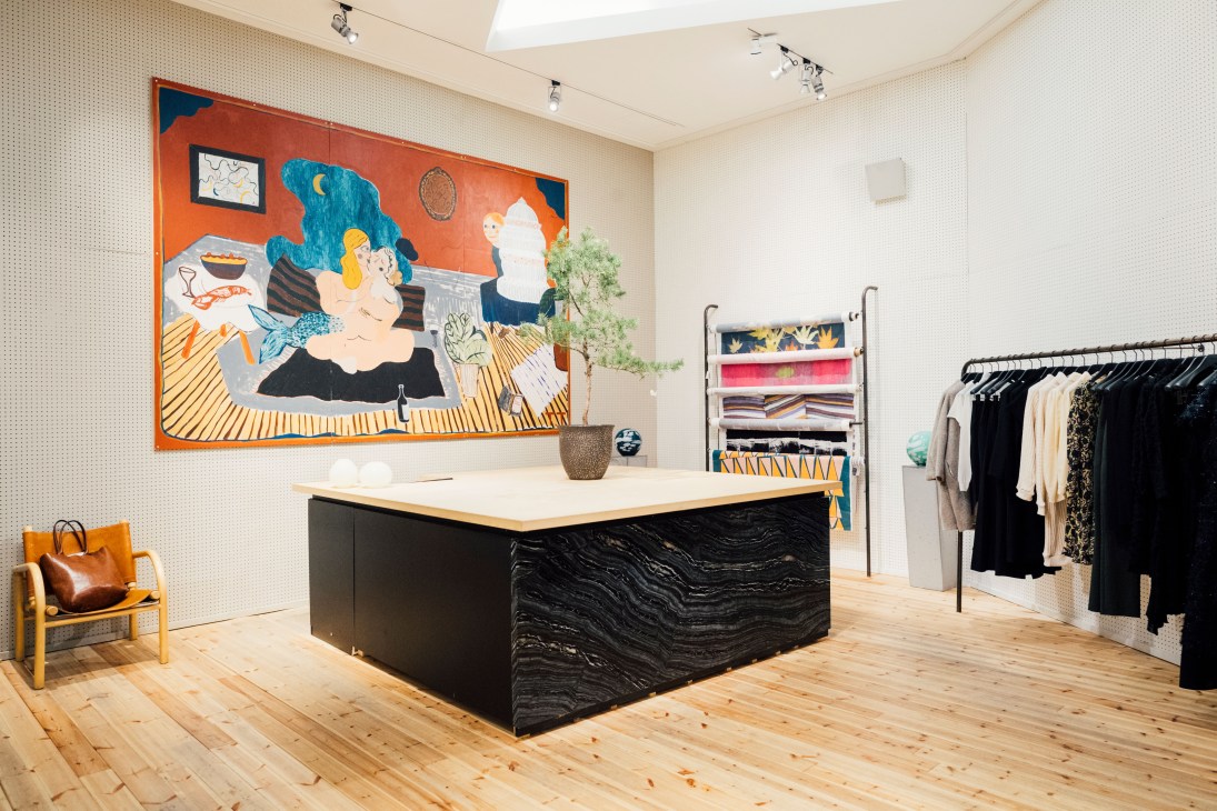 Samuji flagship store interior with colorful abstract painting, black counter, and clothing racks.