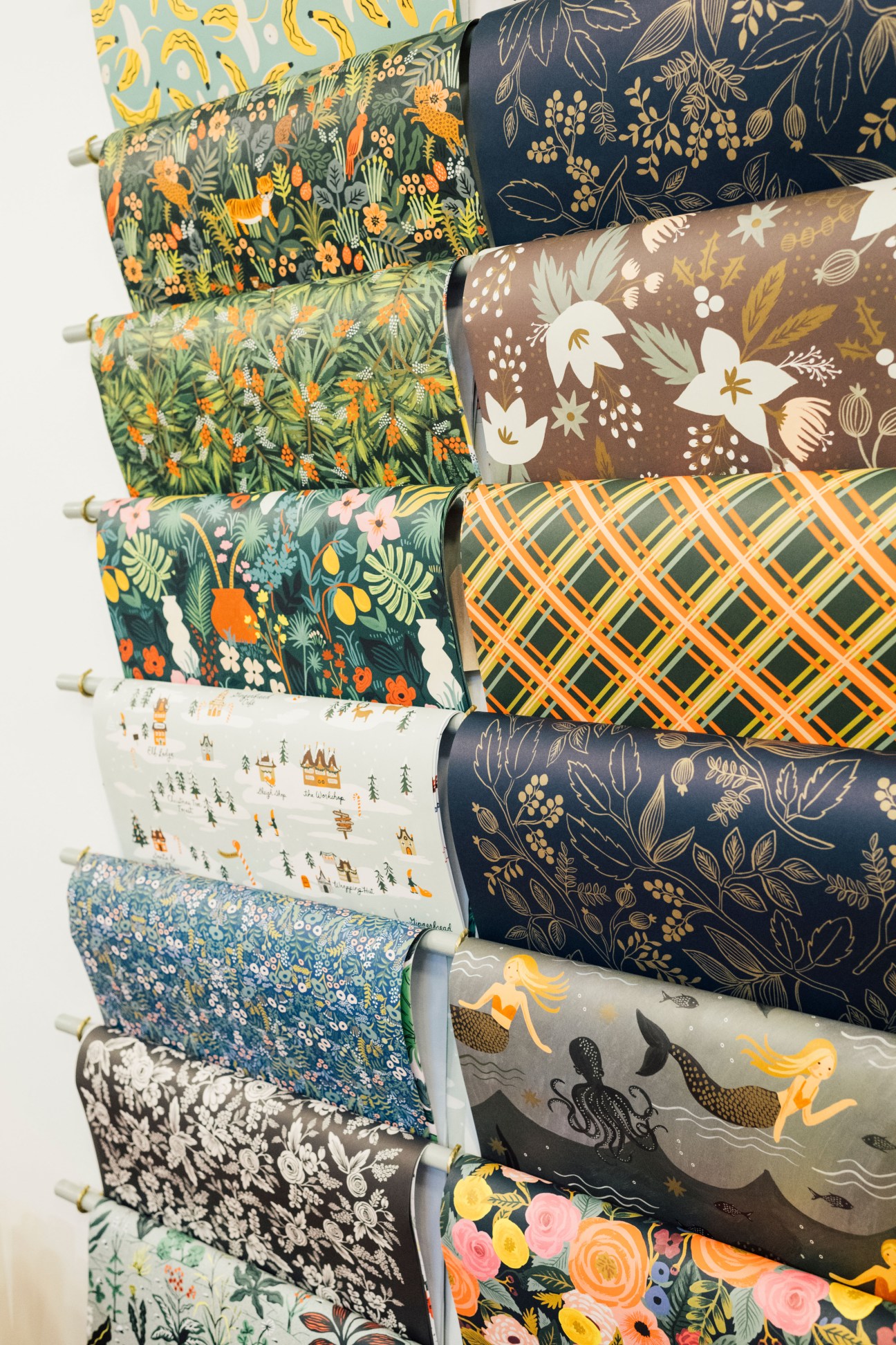 Rolls of decorative gift wrapping paper with various floral and patterned designs in colorful hues.