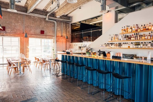 Interior of Tislaamo distillery and bar with blue-paneled counter and wooden chairs