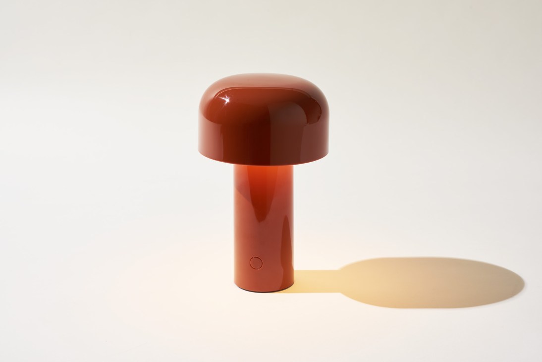 Red portable rechargeable Bellhop lamp by Flos with rounded top and cylindrical base.
