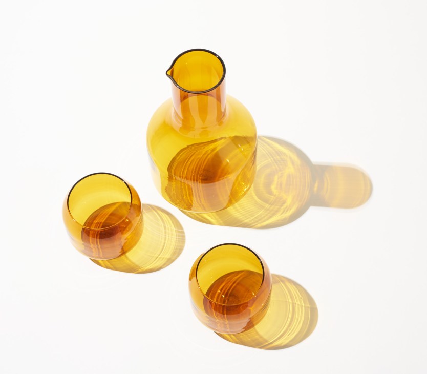Amber glassware set by R+D.Lab featuring a carafe and three drinking glasses with geometric lines inspired by Milan's Velasca Tower.
