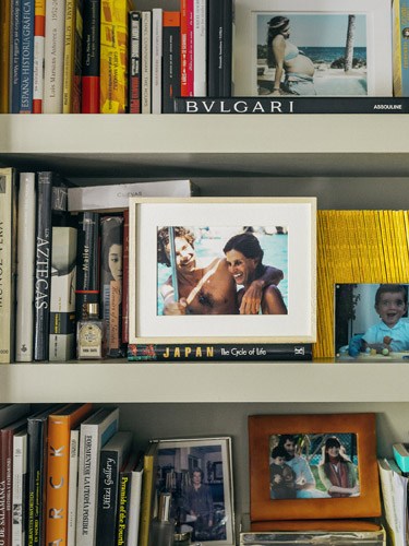 Shelves displaying books, framed photos, and personal mementos including Bulgari and Japan publications.