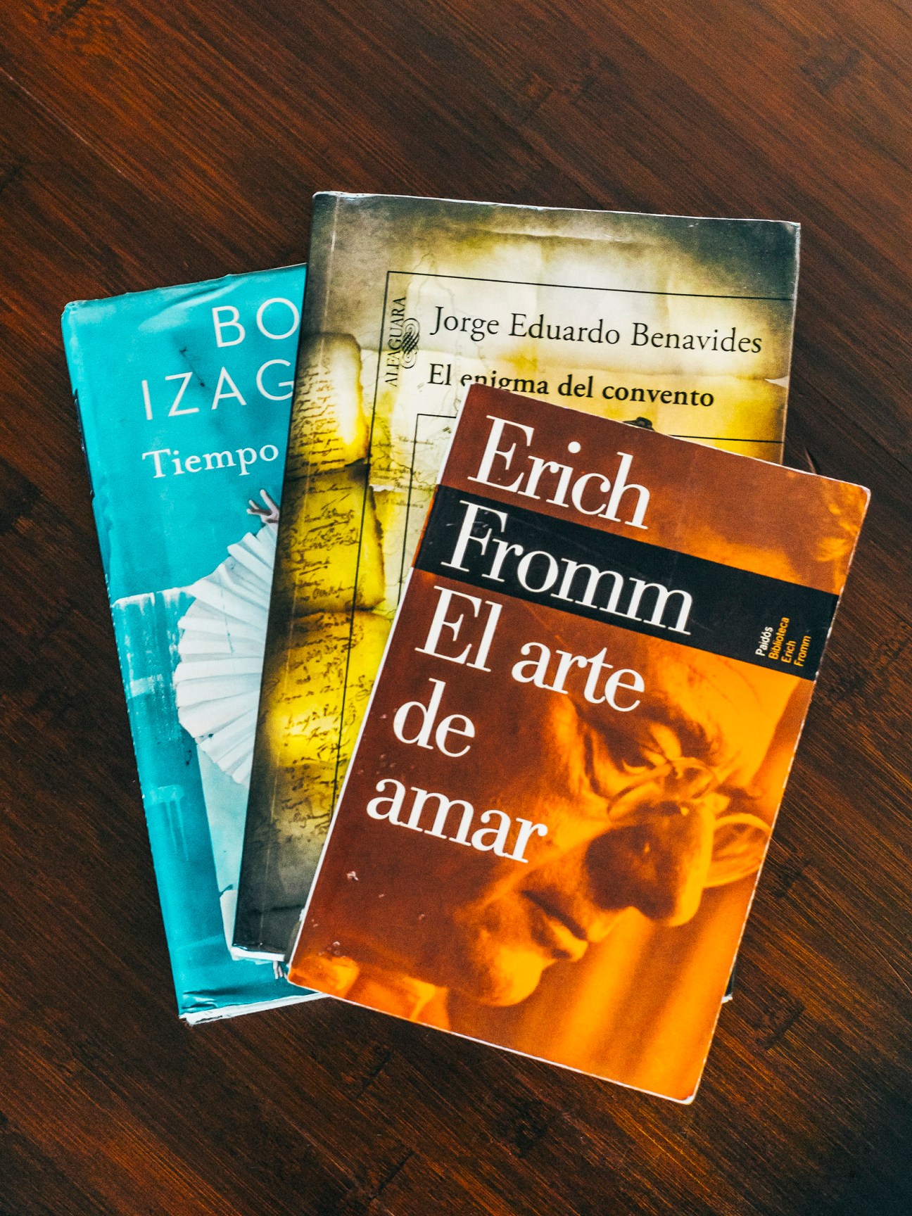 Stack of three books including titles by Jorge Eduardo Benavides and Erich Fromm on wooden surface.