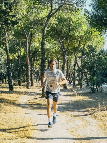 Man jogging on a tree-lined park path wearing athletic attire.