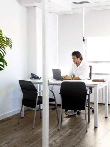 Javier Goyeneche working at his desk in an open office with an empty chair across from him.