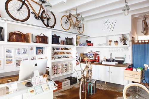 Interior of In Bed retail shop in Sydney with white shelving, hanging bicycles, and workspace.