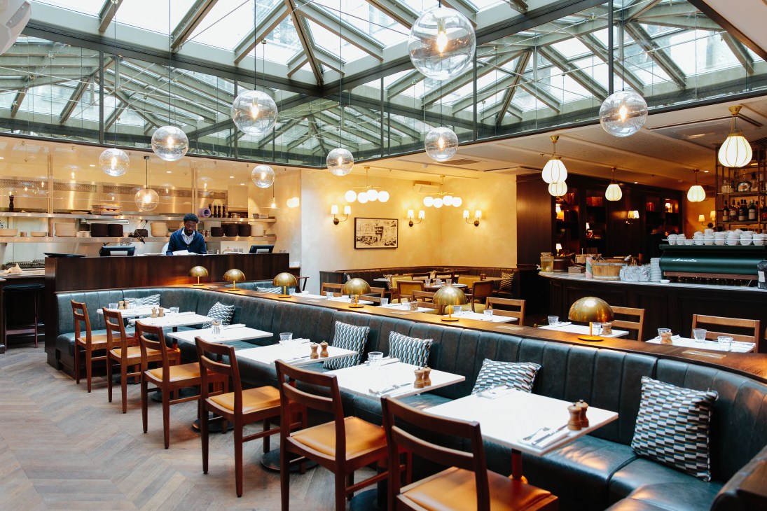 Modern restaurant interior with arched ceiling, wooden tables and chairs at Hoxton Paris.